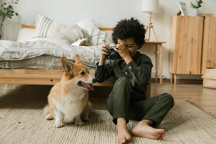 Young boy photographing his pet Corgi dog, showing the companionship and amazing benefits of dogs for kids.