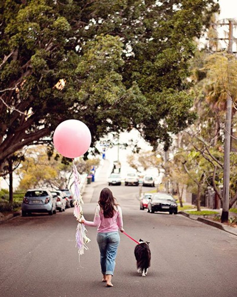 Woman walking her dog with a large pink balloon, symbolizing a farewell and new beginnings for Pretty Fluffy.
