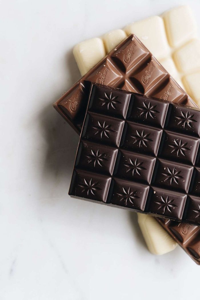 Dark, milk, and white chocolate bars stacked on a light marble surface.