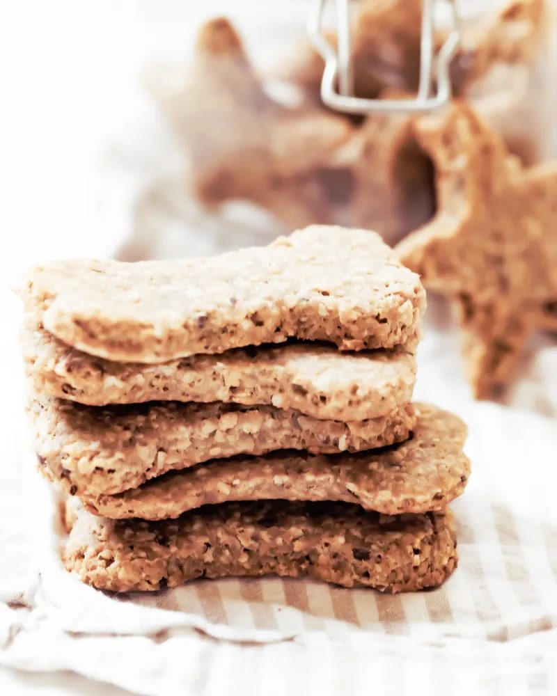 pile of homemade peanut butter and banana dog treats with jar in background