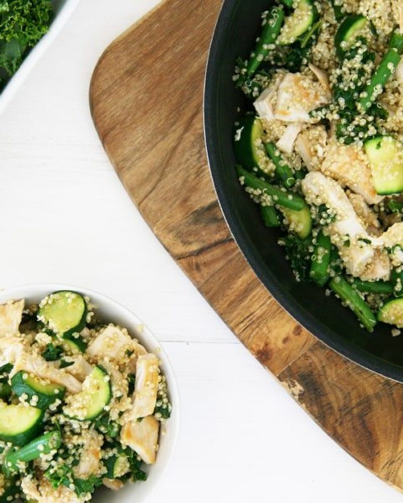 Healthy homemade dog food with chicken, quinoa, and zucchini in a skillet and bowl.